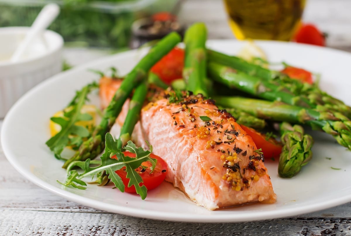 Baked salmon garnished with asparagus and tomatoes with herbs Baked salmon garnished with asparagus and tomatoes with herbs